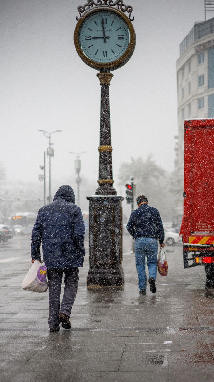 snowy city street with clock tower and shoppers